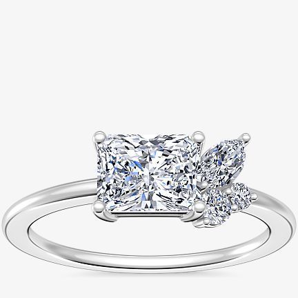 Asymmetrical cluster engagement ring featuring a main radiant diamond and smaller accent diamonds in 18k white gold